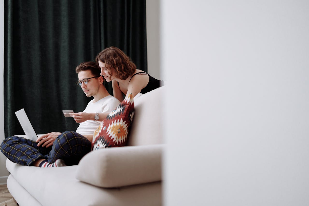 why-choose-us A couple sits comfortably on the couch while shopping online together.