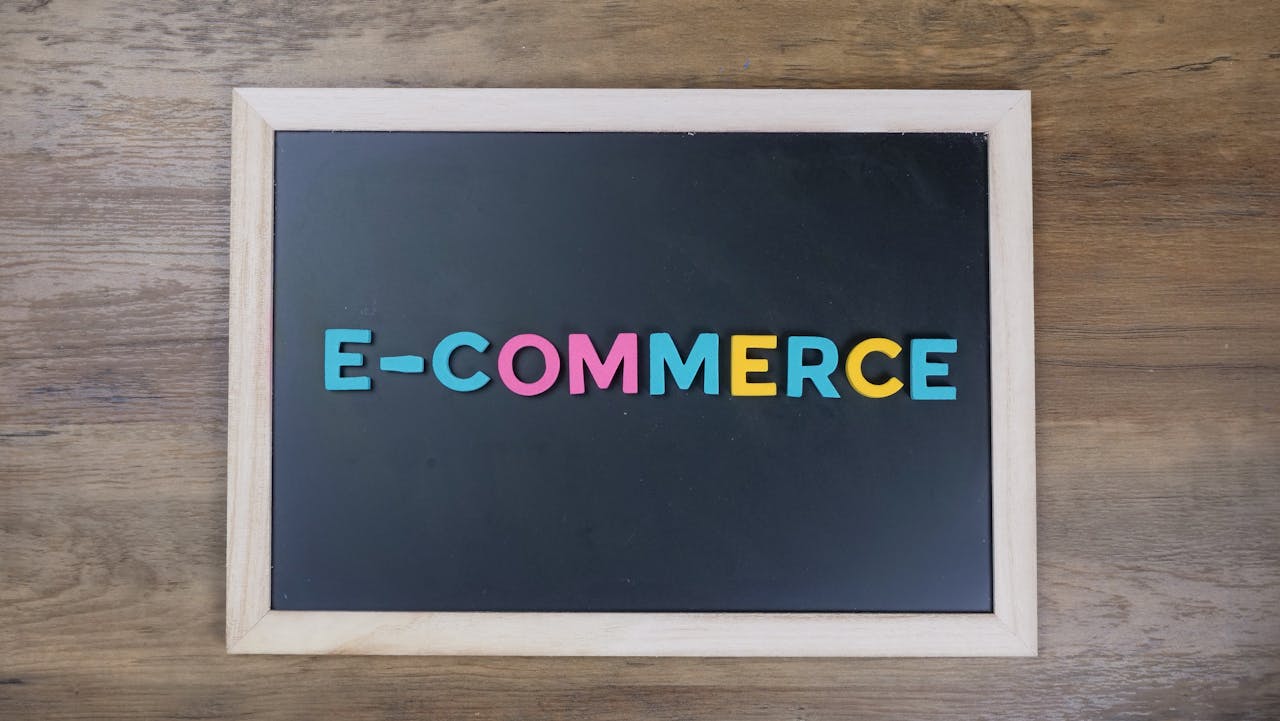 hero-img-02 Colorful letters spelling e-commerce on a wooden framed blackboard.